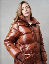 Campera puffer larga de abrigo marca BCBG Maxazria, color beige. Cuenta con capucha desmontable, cuello alto envolvente, cierre frontal bidireccional con solapa de botones a presión, bolsillos laterales, puños internos elastizados y tajos laterales con cierre en el bajo.