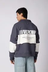 Buzo tipo polo de calce relajado con diseño de bloques de color en tonos marrón y blanco. Presenta cuello polo, cierre frontal parcial y logo estampado en el pecho. Confeccionado en tejido pesado con estructura.
