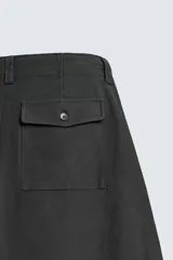 Pantalón de corte balloon fit, color negro, con bolsillos laterales de vivo y bolsillos traseros con solapa. Presenta cierre frontal con cremallera y botón.