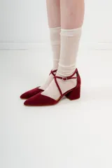 Zapato de tacón bajo color negro, con punta en V, tiras cruzadas en el empeine y cierre de hebilla en el tobillo. El tacón es ancho y mide 5 cm.