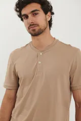 Remera tipo henley de manga corta, color beige, con cuello redondo y cartera de botones frontal.