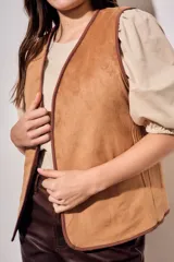 Chaleco sin mangas de color marrón, con diseño acolchado y bordados florales en toda la superficie. Presenta un corte recto y terminaciones con ribetes al tono.