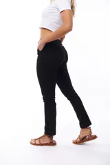 Pantalón negro de corte ajustado, con cinturón fino marrón.