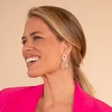 Caravanas colgantes compuestas por dos aros ovales de diferentes tamaños, elaboradas en plata 925. El aro superior presenta un acabado texturizado con incrustaciones de circonias, mientras que el aro inferior posee un diseño liso y pulido.