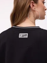 Sweater negro de corte regular con cuello redondo y puños y dobladillo acanalados con detalles de rayas grises. Presenta estampados blancos en el frente con el texto "Rusty Club" y logos de la marca.