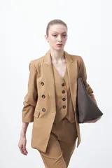 Blazer sastrero negro de doble botonadura con botones marrones, cuello solapa y mangas tres cuartos. Tiene dos bolsillos delanteros con solapa.