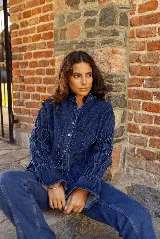 Camisa de jean azul oscuro con cuello mao, cierre frontal con botones metálicos y mangas largas con detalle de frunces elásticos.