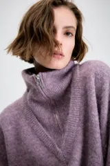 Jersey de punto con cuello alto y cierre frontal de cremallera metálica, de manga larga con puños ajustados y diseño holgado.