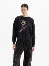 Buzo de cuello redondo y mangas largas, con calce amplio y largo a la cadera. Presenta una estampa frontal con diseño de esquiadora y la frase 'Après Ski', junto con un logo bordado en la espalda.