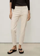 Jeans tiro alto corte mom-fit de algodón elástico, en color beige claro, con cinco bolsillos, trabillas y cierre delantero de cremallera y botón.
