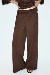 Pantalón de tiro alto con diseño de pierna ancha, confeccionado en tejido con efecto ante. Cuenta con cintura elástica y bolsillos laterales ocultos en la costura.