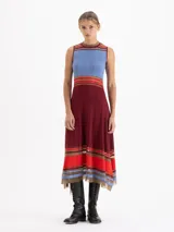 Vestido midi de punto sin mangas con diseño plisado. Presenta un corte evasé con rayas horizontales en tonos rojo, rosa y negro en el cuello, la cintura y el ruedo, el cual cuenta con terminaciones irregulares y detalles de transparencia.