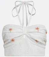 Blusa corta blanca de algodón con bordado de palmeras color naranja, escote halter y espalda descubierta.