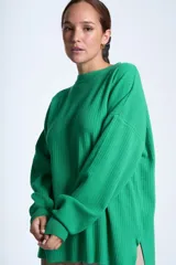 Sweater azul eléctrico de punto acanalado, con cuello redondo y mangas largas. Corte holgado con aberturas laterales.