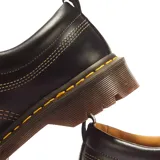 Zapatos de cuero negro Dr. Martens modelo Lowell, con puntera moc toe, costuras contrastantes amarillas y suela gruesa acanalada.