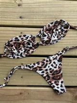 Conjunto de bikini con estampado animal print, compuesto por un corpiño triangular con tiras finas y una bombacha cavada con tiras laterales ajustables.