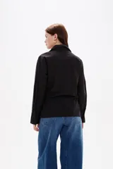Camisa blanca de algodón con diseño cruzado y anudado lateral, cuello camisero y mangas largas con puños.