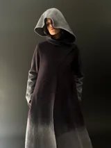 Tapado largo de lana merino color gris oscuro con teñido degradado en gris claro en ruedo, mangas y capucha. Tiene corte recto, bolsillos laterales y cierre cruzado con broches a presión ocultos en los hombros.