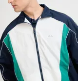 Campera deportiva Ellesse modelo Sako, diseño en bloques de color azul marino, blanco y verde, con cierre frontal completo, cuello alto y detalles de líneas blancas en las mangas.