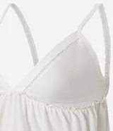 Blusa blanca de algodón y poliéster con breteles finos, escote en V con lazo ajustable y detalles de recortes decorativos.