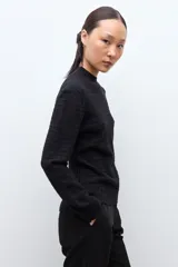 Sweater de punto color crudo con cuello alto tipo media polera, manga larga y diseño con textura de líneas horizontales. Presenta un borde inferior con terminación ondulada.