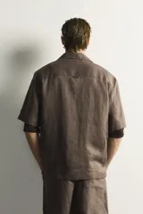 Camisa de lino color blanco, con ajuste relajado, cuello bowling, manga corta y cierre frontal con botones.
