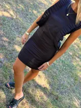 Vestido corto negro sin mangas, con detalle de volados plisados verticales en el frente y diseño ajustado al cuerpo.