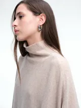 Poncho amplio de cuello alto, confeccionado en hilado con lana y cashmere, con diseño de caída recta y botones laterales.