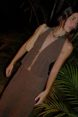 Top de tejido de punto color marrón con escote profundo, diseño halter y cierre frontal con cordones. Presenta espalda abierta y acabado con sutil brillo.