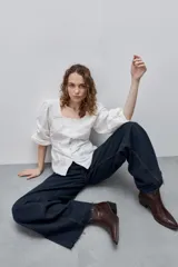 Jean wide leg negro de tiro alto, confeccionado en denim rígido, con diseño de cinco bolsillos, presillas para cinto, cierre frontal con botón y ruedo desflecado.
