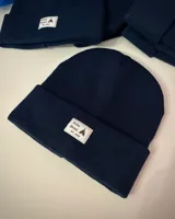 Gorro de lana azul marino con dobladillo y parche frontal con el logo de la marca Tribe Brand.