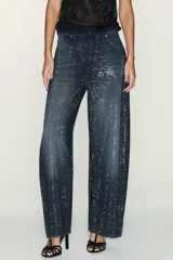 Jeans de tiro medio con corte baggy y cinco bolsillos. Presenta un diseño de estampado floral creado mediante la aplicación de strass a contraste sobre el denim. Cierre frontal con cremallera y botón metálico.