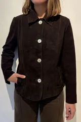 Blazer de gamuza color chocolate, con cuello clásico, cierre frontal de botones nacarados y bolsillos laterales.