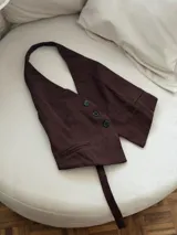Chaleco marrón con escote halter y cierre frontal con botones.