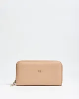 Billetera Flavia Fichero de símil cuero color beige, con cierre perimetral y logo metálico dorado en la parte frontal.