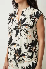 Blusa negra sin mangas, con cuello mao y abertura frontal con botones. Presenta frunces en la zona de los hombros, dándole un calce holgado.