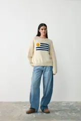 Sweater de lana color crudo con diseño tejido de la bandera de Uruguay en el frente. Presenta cuello redondo, mangas largas y corte holgado.