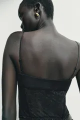 Top estilo corset con copas de tejido satinado y cuerpo de encaje semitransparente con varillas. Presenta tirantes finos ajustables y cierre lateral con cremallera oculta.