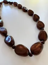 Collar de cuentas ovaladas de resina con efecto marmolado en tonos marrones, unido por pequeñas esferas y cierre metálico dorado.