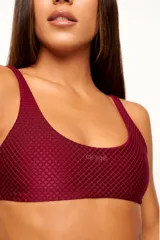 Top deportivo color verde oscuro, con tirantes finos y espalda descubierta. Diseño reversible con un lado brillante y otro con textura 3D tipo colmena.