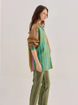 Camisa de algodón liviano con diseño de rayas multicolor, corte holgado, cuello camisero, mangas largas y bolsillo frontal.