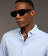 Camisa blanca de corte regular, confeccionada en tejido Oxford de algodón, con cuello inglés, mangas largas y cierre frontal abotonado.