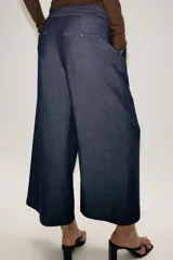 Pantalón culotte de tiro medio con pernera ancha y corta. Presenta nervios marcados en la parte delantera, bolsillos laterales y cierre frontal con cremallera, botón interior y hebilla ajustable en la cintura.