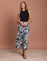 Pantalón capri estampado con flores en tonos azul, blanco y negro. Tiene pretina elastizada en la parte trasera y bolsillos delanteros.
