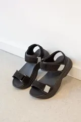Sandalias de plataforma estilo deportivo en color negro, con tiras ajustables de velcro con textura tipo reptil y detalles en color gris claro.