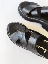 Sandalias negras de cuero con tiras cruzadas, plataforma track y hebilla lateral.