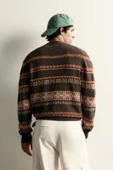Cárdigan marrón de punto jacquard con mezcla de algodón y lino, con cuello en V, cierre frontal de botones y bolsillos en la cadera. Presenta un diseño estampado de franjas horizontales con patrones geométricos en tonos naranjas, blancos y lilas.