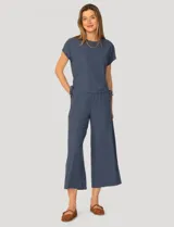 Conjunto de dos piezas compuesto por una remera de manga corta con cuello redondo y frunces laterales ajustables, y un pantalón de corte ancho con cintura elástica y bolsillos laterales.