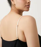 Conjunto de pijama negro, compuesto por un top de tirantes con encaje blanco en el escote y un short con encaje blanco en el ruedo.