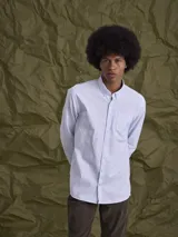 Camisa de manga larga confeccionada en tejido Oxford de algodón, con cuello abotonado y bolsillo frontal en el pecho.